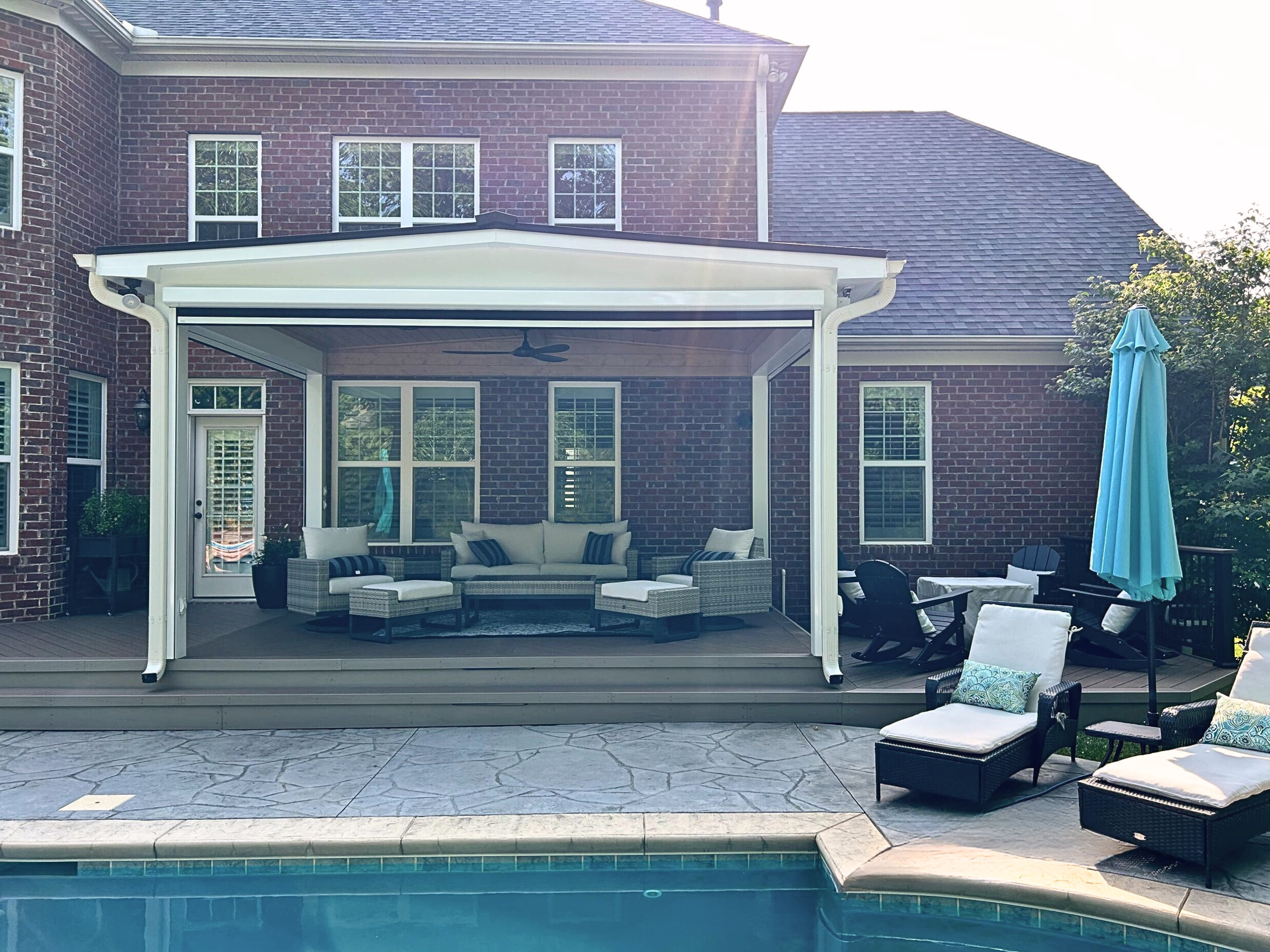 Custom outdoor living space in Concord, NC featuring an open porch over a timbertech deck overlooking a pool and patio.