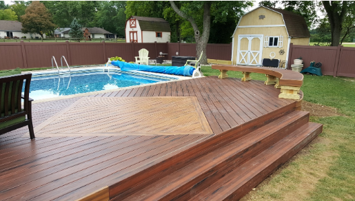 Wood deck with bench connected to side of pool.