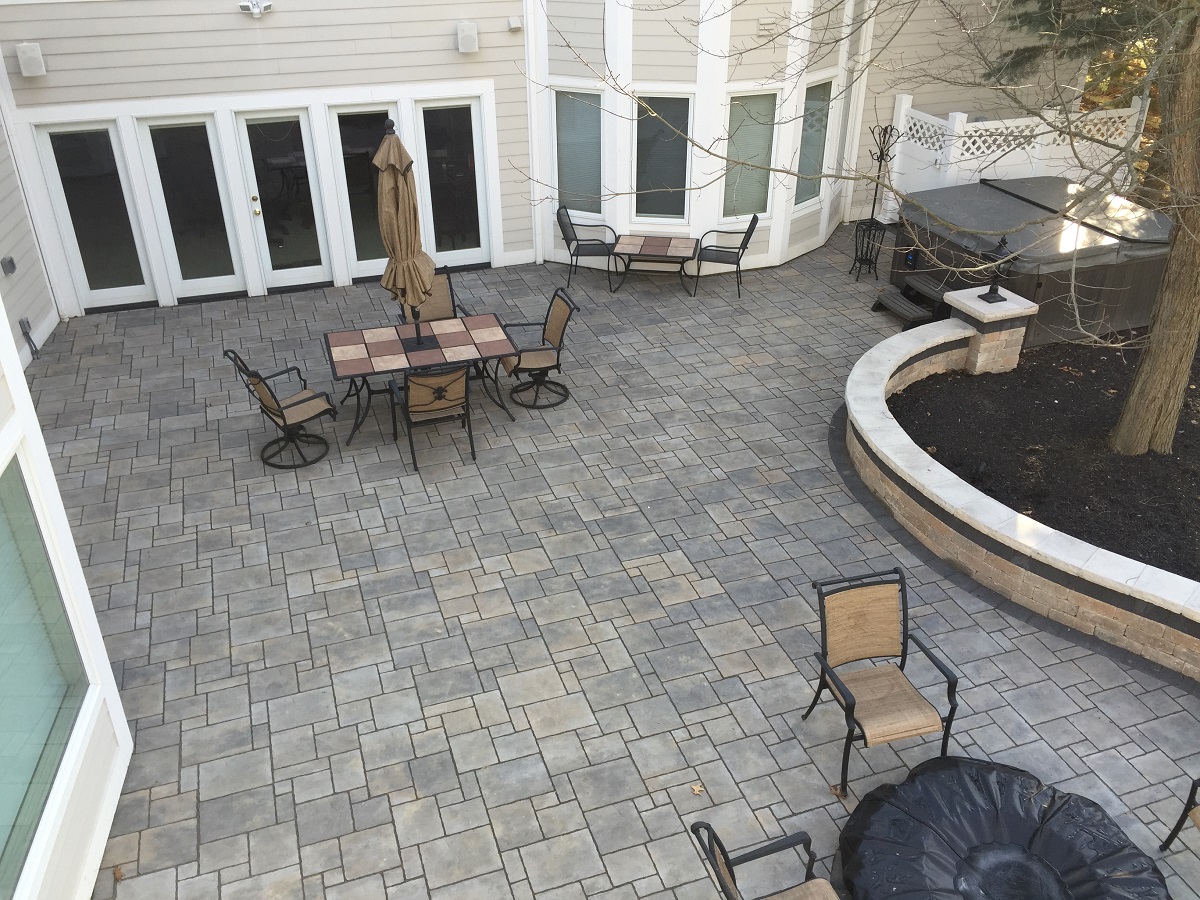 Archadecl custom stone patio with outdoor furniture, retaining wall for plant area and a hot tub