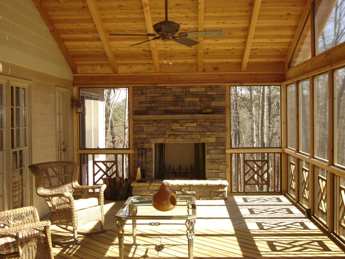 Screened porch with stone fireplace and vaulted wood ceiling with a fan