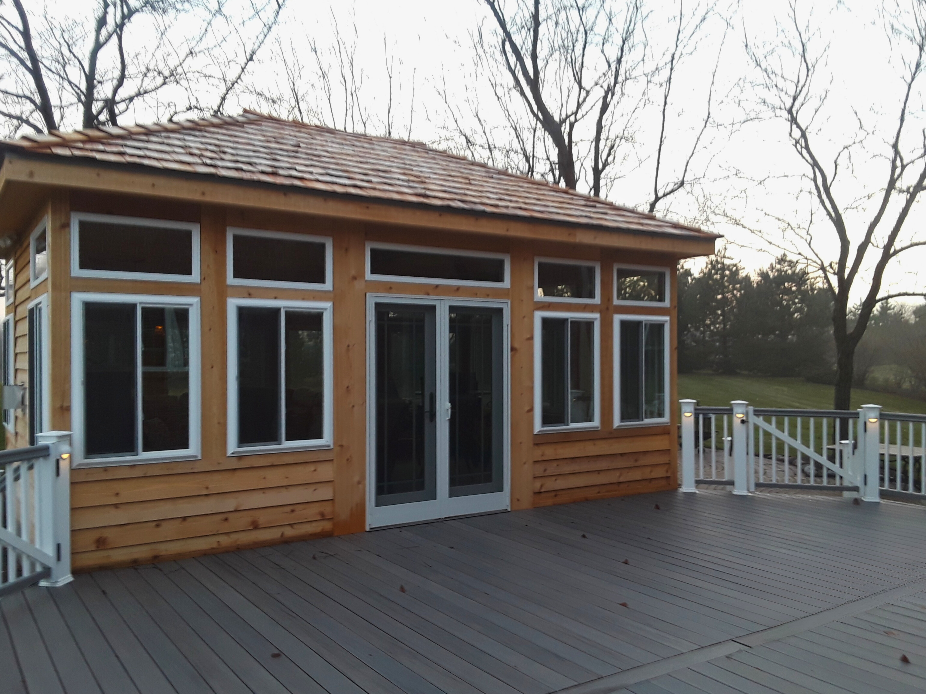 Detached four-season room with large windows and a grey composite deck with white railing lights, Barrington, IL.