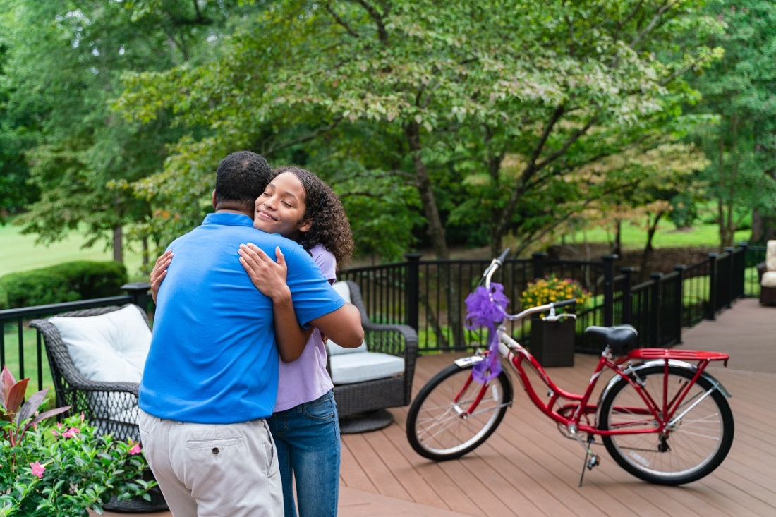 man and woman hugging near a bike on a deck