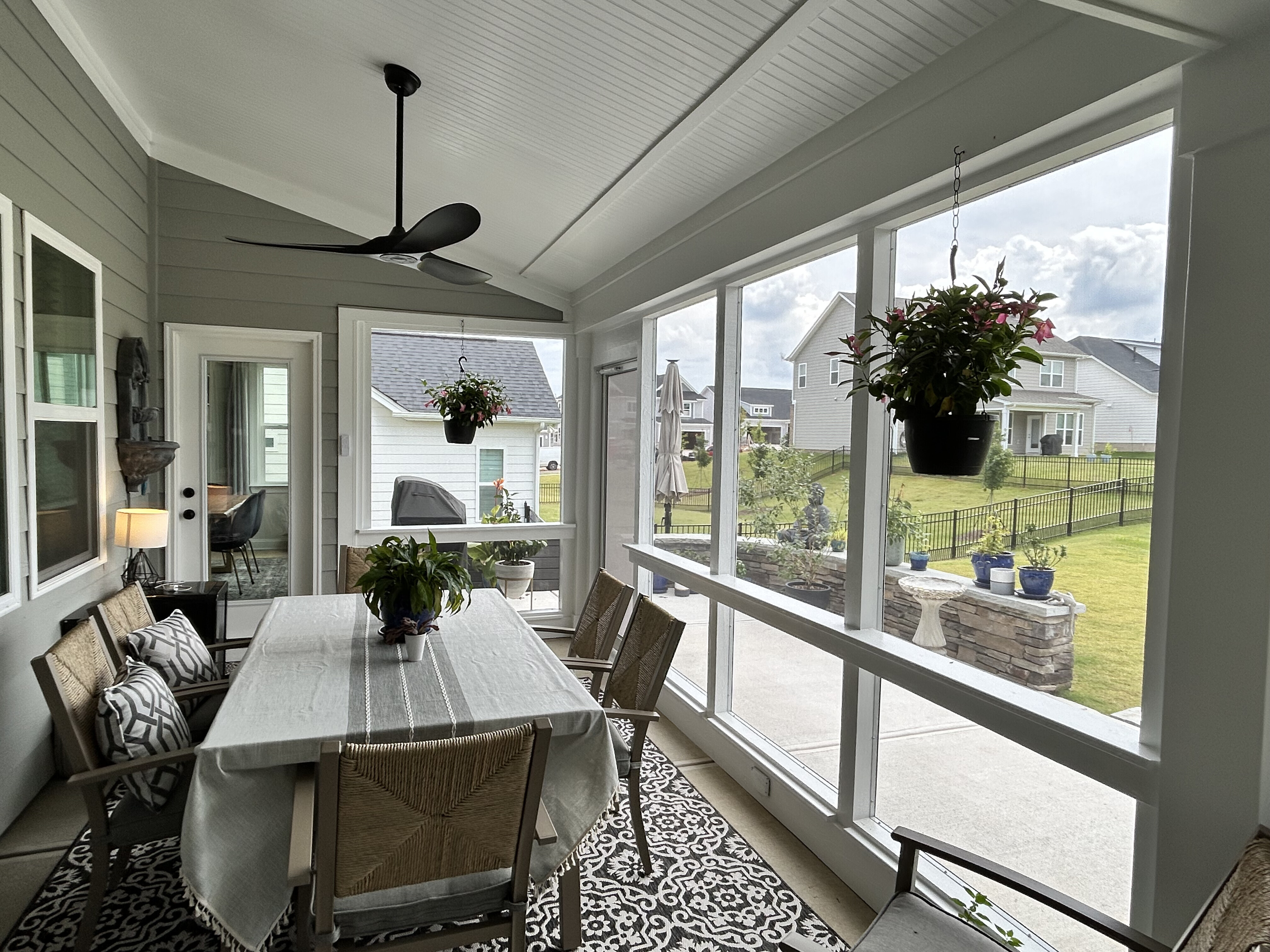 Inside view of a screened porch with a  dining table, ceiling fan, and outdoor rug in Charlotte, NC.