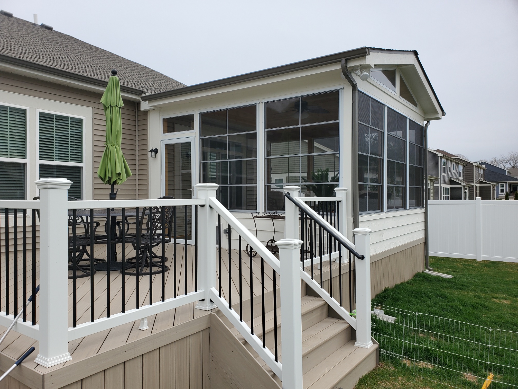 Custom composite deck outside of a 3-season room with 4-track windows by Archadeck of Chicagoland.