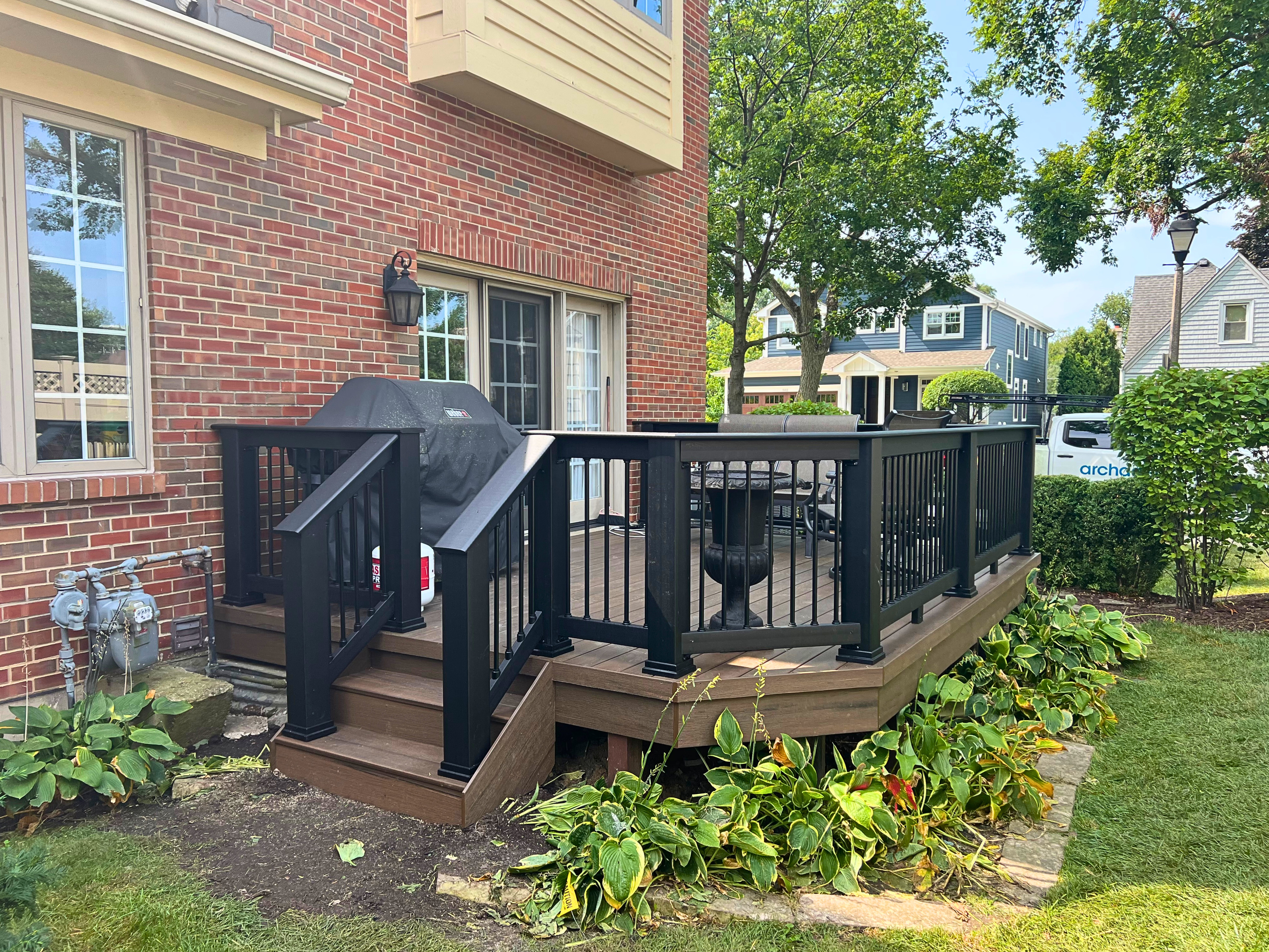 Timbertech Deck with brown decking and black rails on a brick house in Elmhurst, IL.