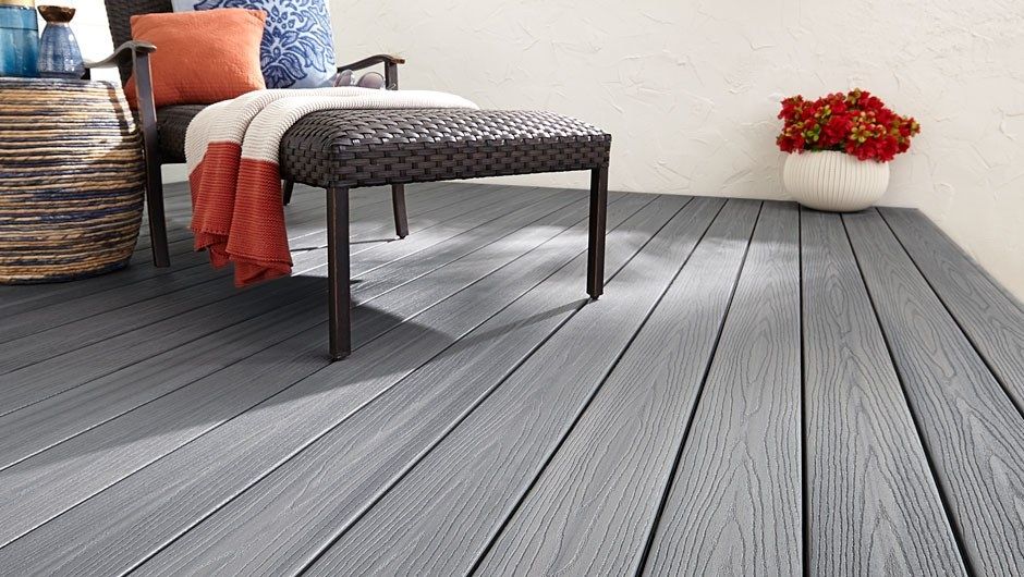 Gray porch with a wood looking texture, outdoor furniture, potted plant, and a white stucco wall