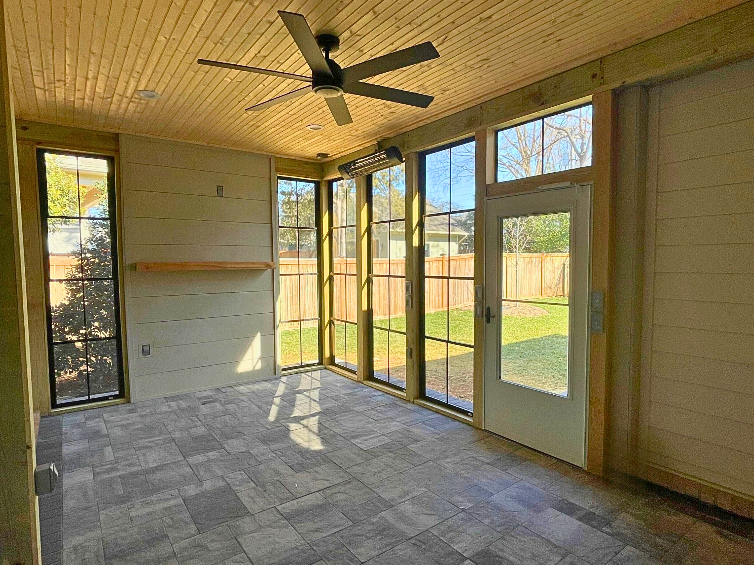 Patio enclosure with eze-breeze windows and solid wood wall for a TV.