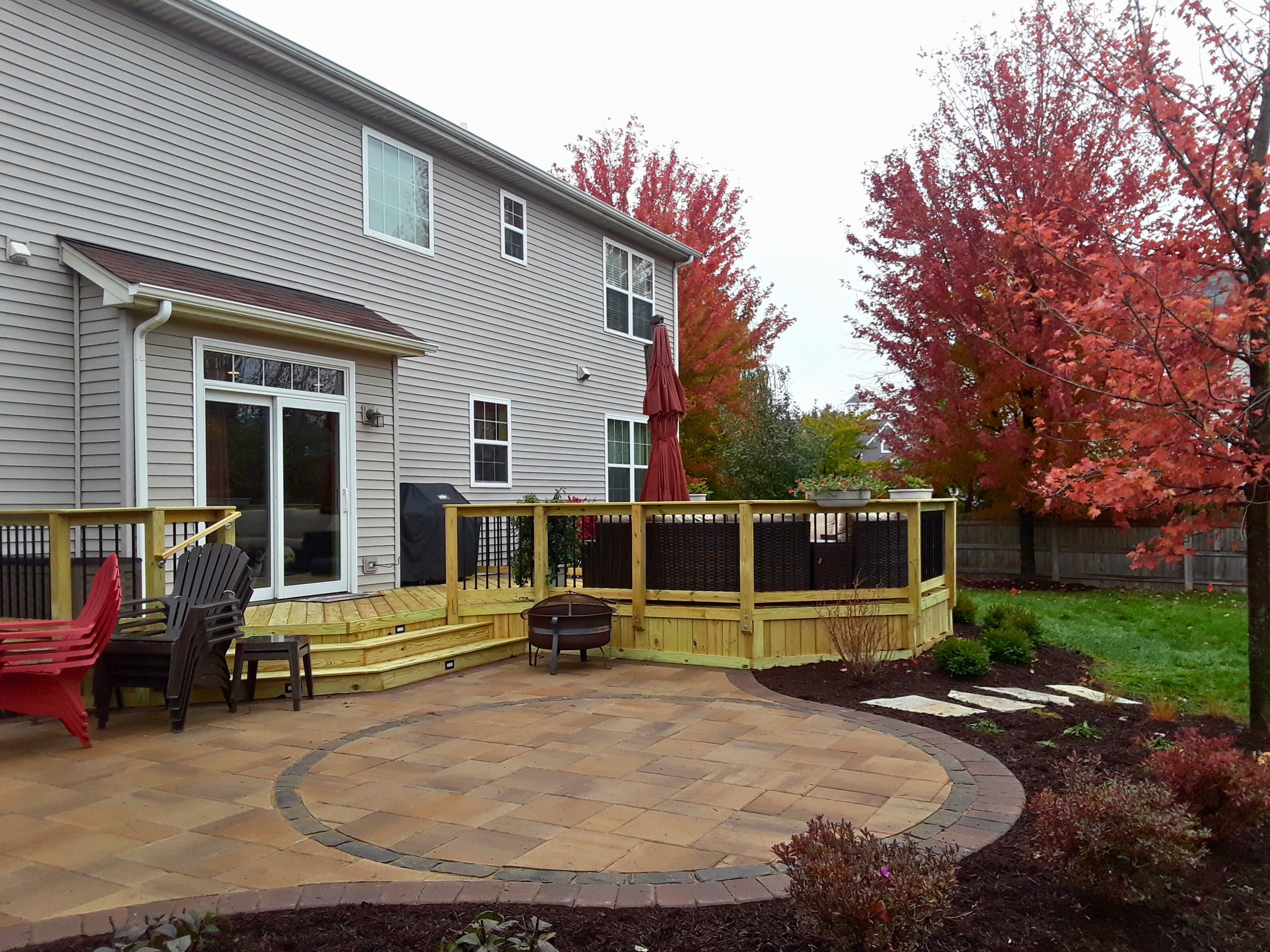 Elevated wood deck with a step down to a paver patio installation in Oswego, IL.