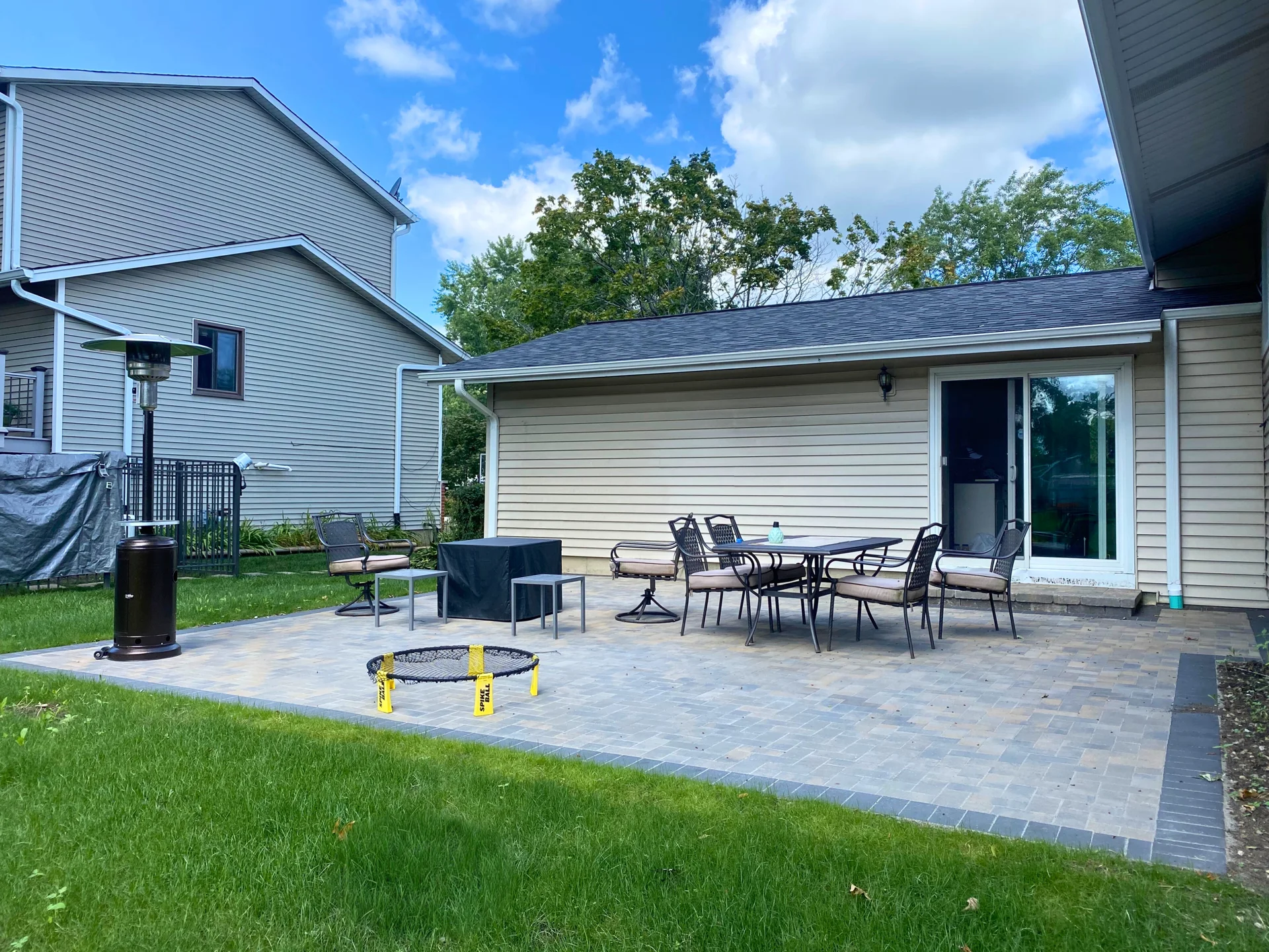 Custom paver patio with dining furniture, outdoor heater, and games in Hoffman estates.