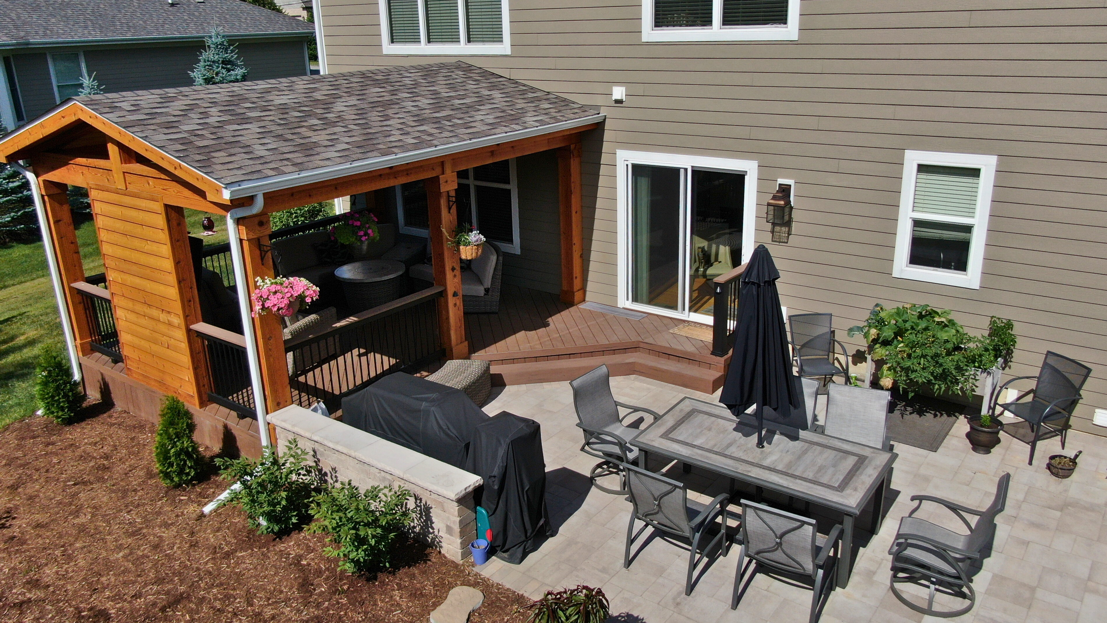 Stunning open porch over a composite deck with a step down to a paver patio installed by Archadeck of Chicagoland-Naperville.