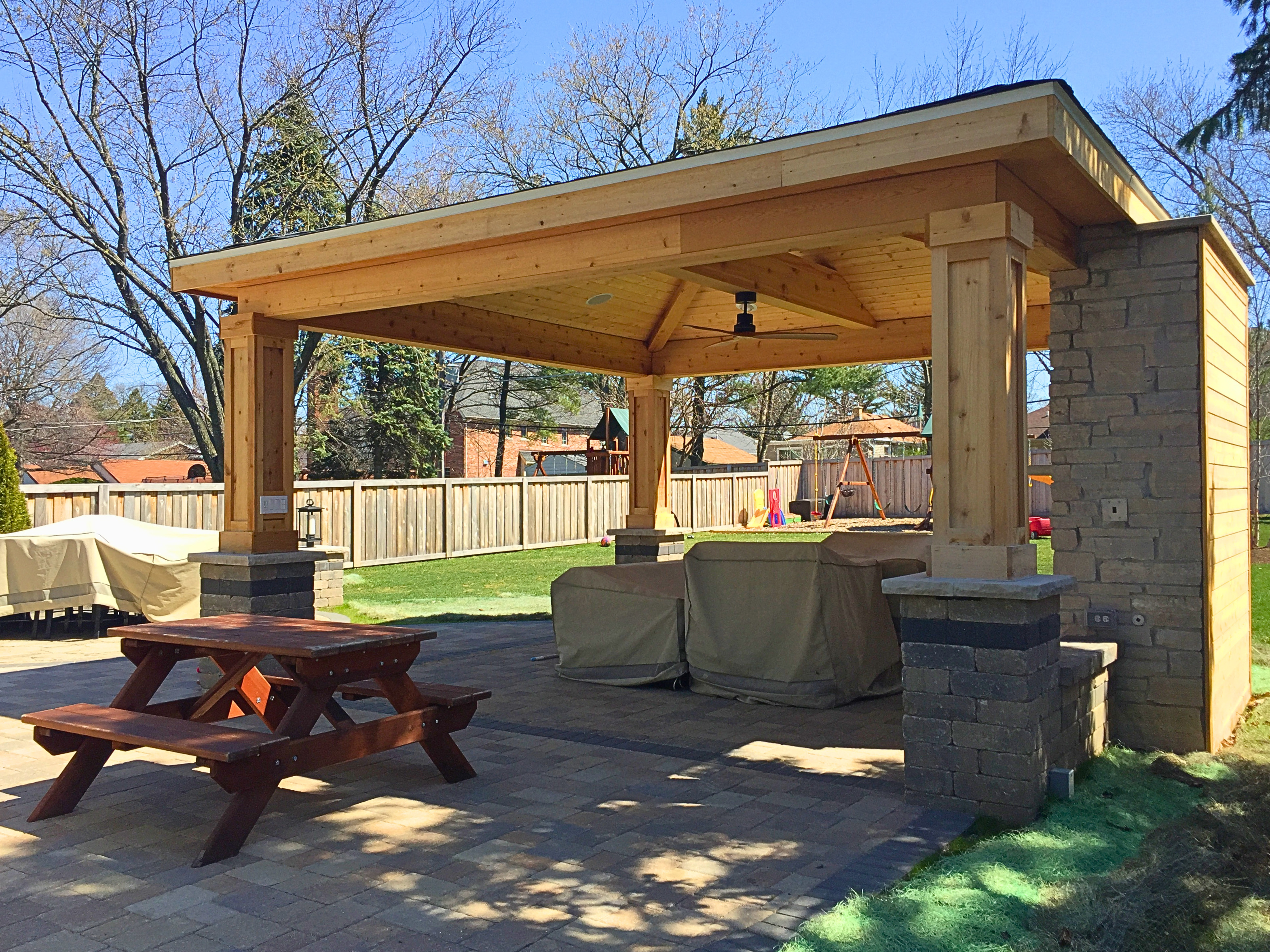 Open porch with a stone fireplace over a paver patio in Elmhurst, IL.