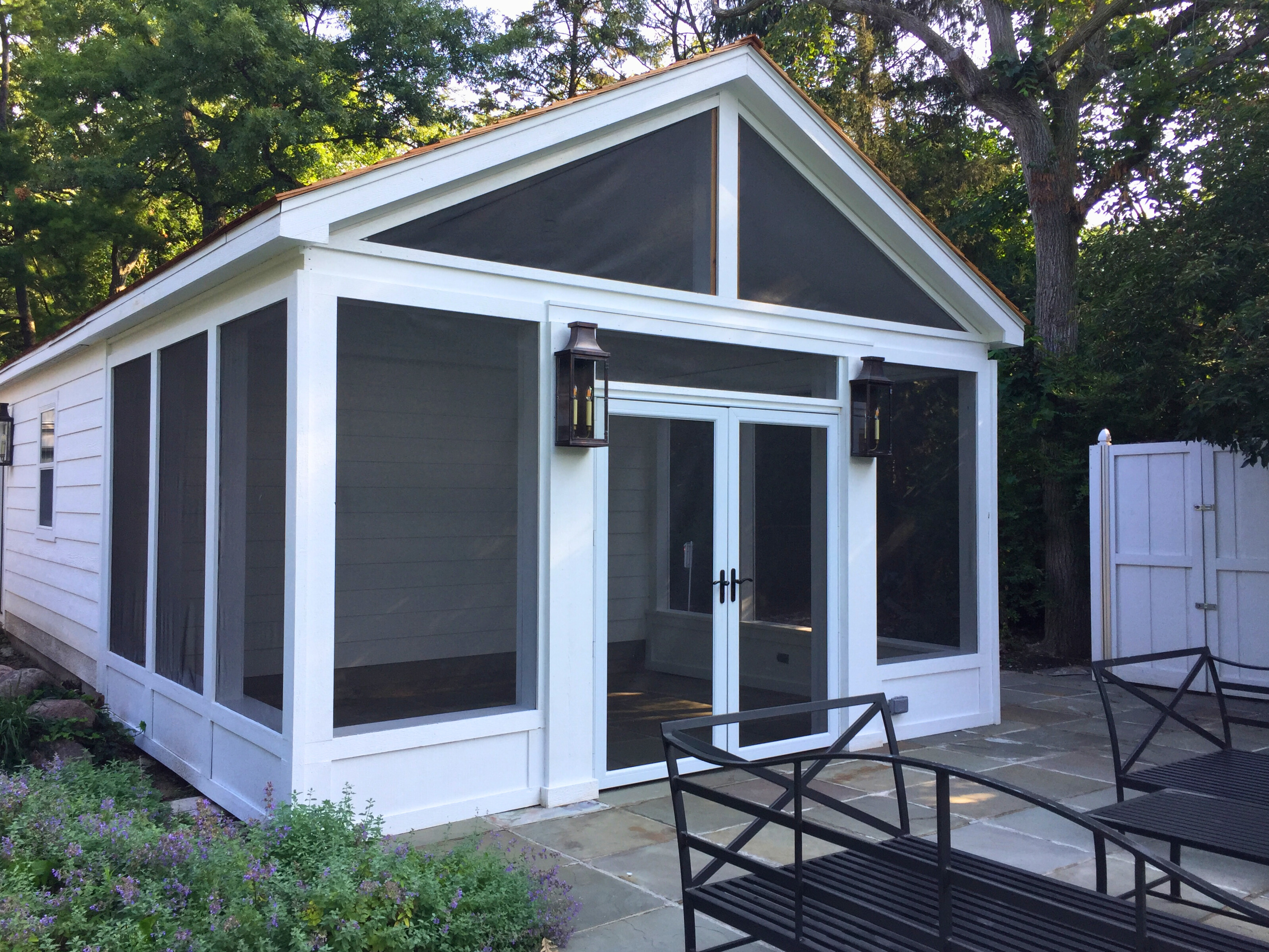 Custom screened porch with white outside and lantern lights.