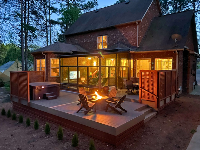 Custom composite deck with integrated hot tub, fire pit, and enclosed sunroom, built by Archadeck of Charlotte.