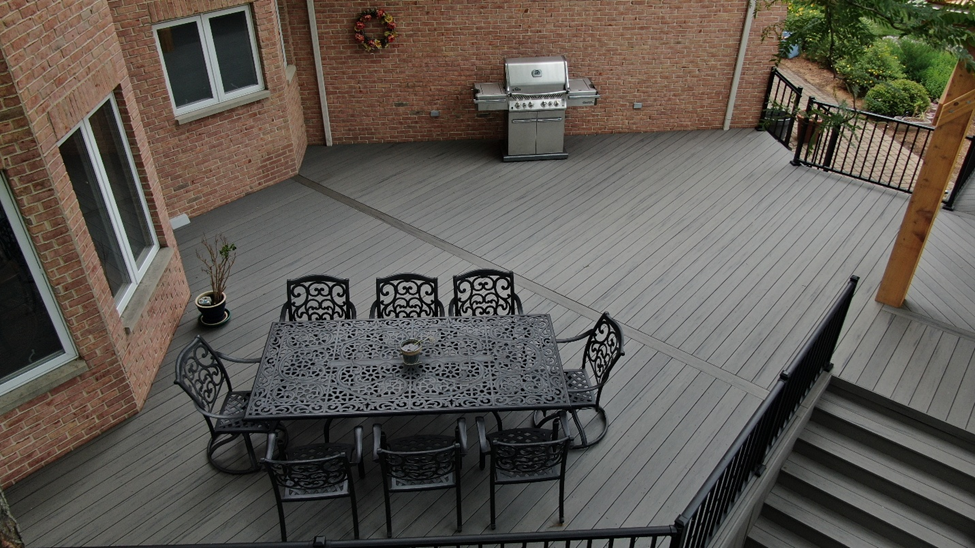 High-angle view of a low-maintenance grey composite deck with black metal railing and large dining table, installed by a Charlotte deck contractor.