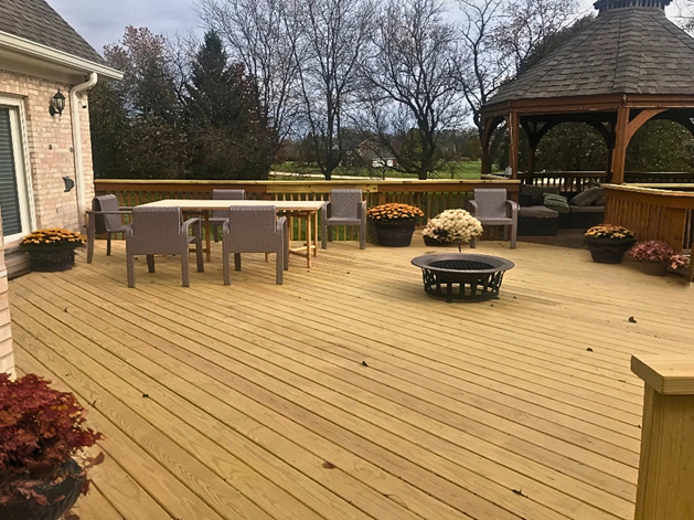 Spacious wood deck with dining set and fire pit, connecting a residential home to a separate wooden gazebo in the Charlotte area. 