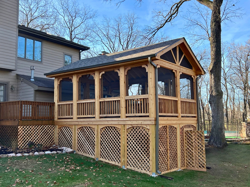 Large, custom-built wooden screened gazebo with a gabled roof and lattice skirting, attached to a house in Homer Glen.