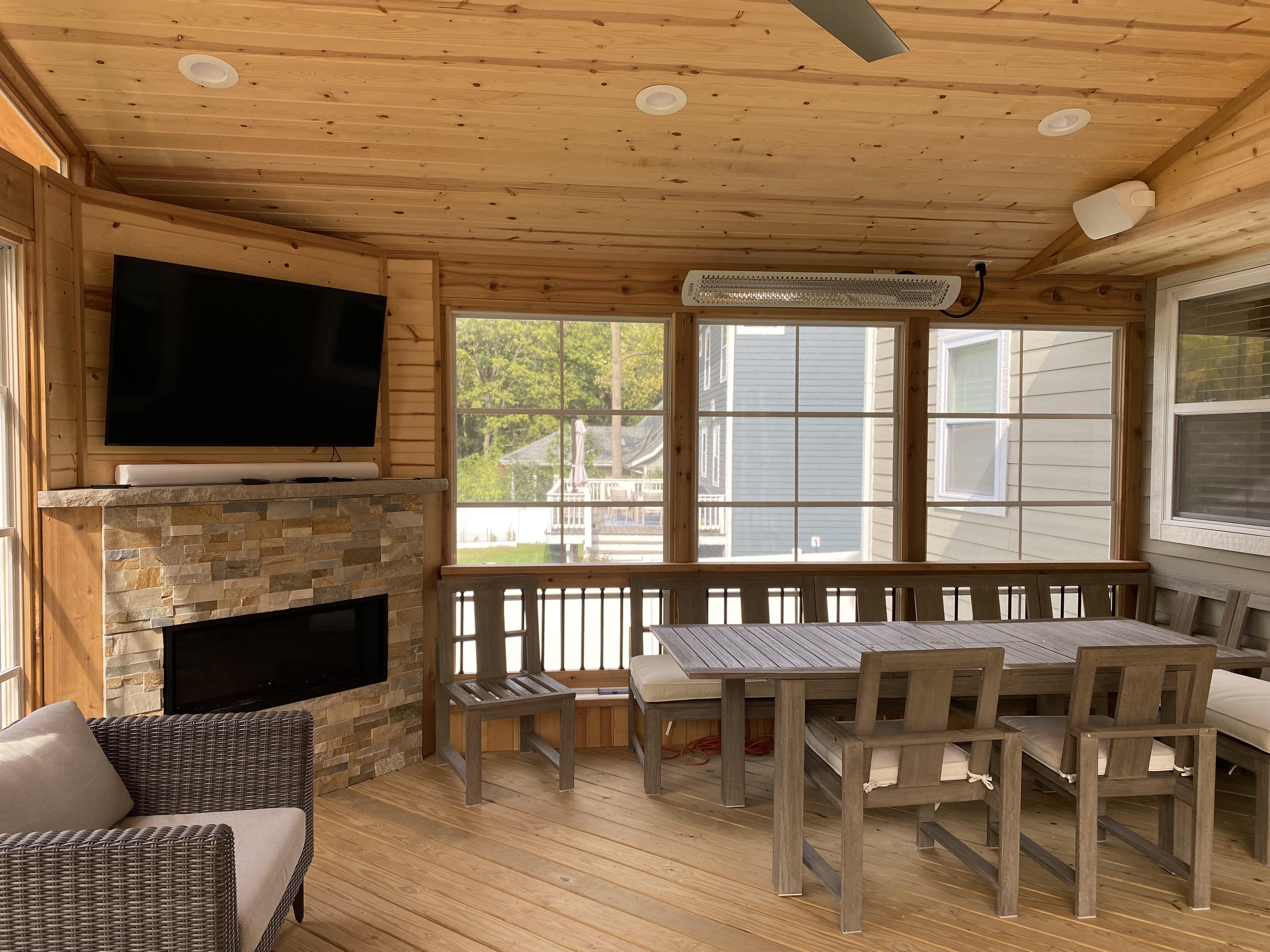 View of inside a custom Archadeck three season room with vertical 4-track windows and a custom fireplace.