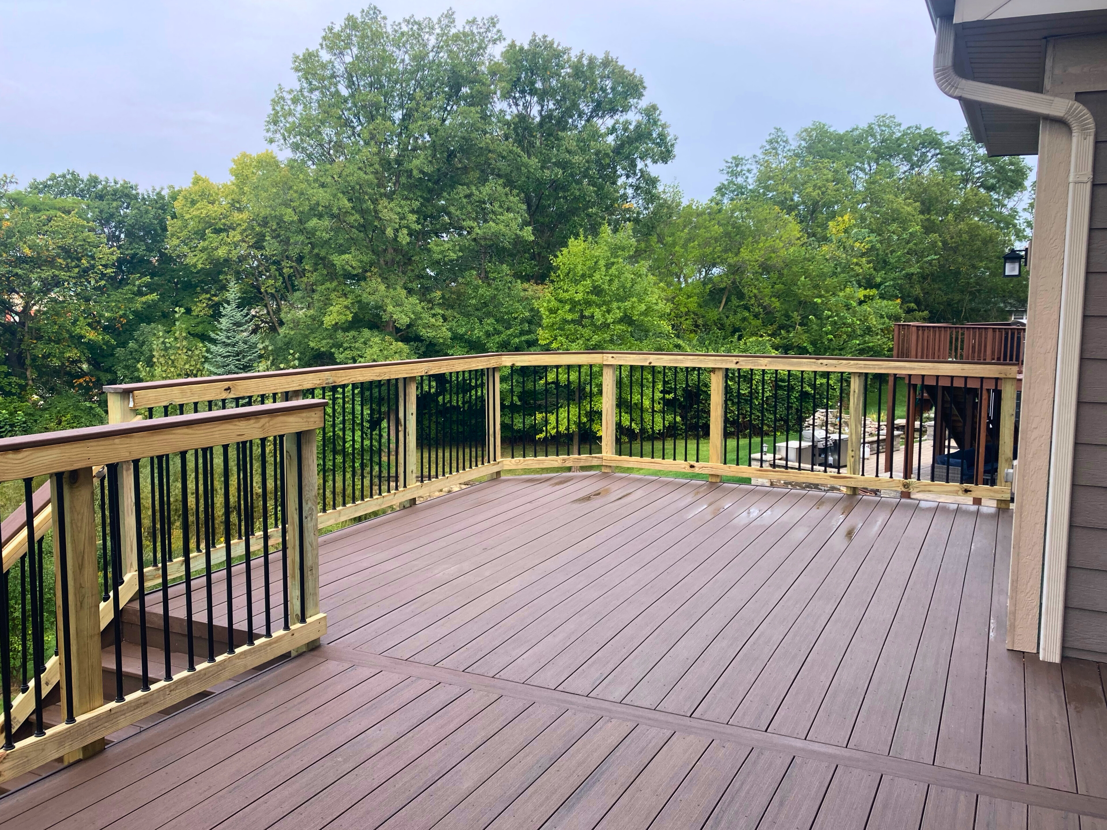 An elevated composite deck featuring dark brown decking and black railings, built by a composite deck builder in Woodridge.
