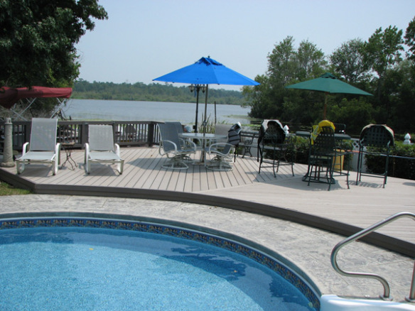grey color deck next to a pool on a property that is waterfront