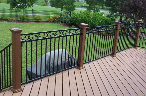deck with iron railing that overlooks grassy backyard