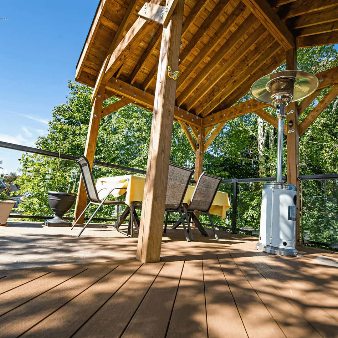 Deck area photo with backyard lawn and trees in the background