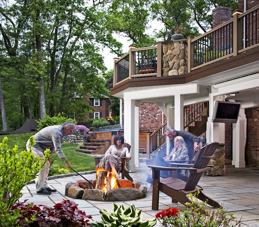 Two pairs of adult couples outside at their fire pit with their deck in the background