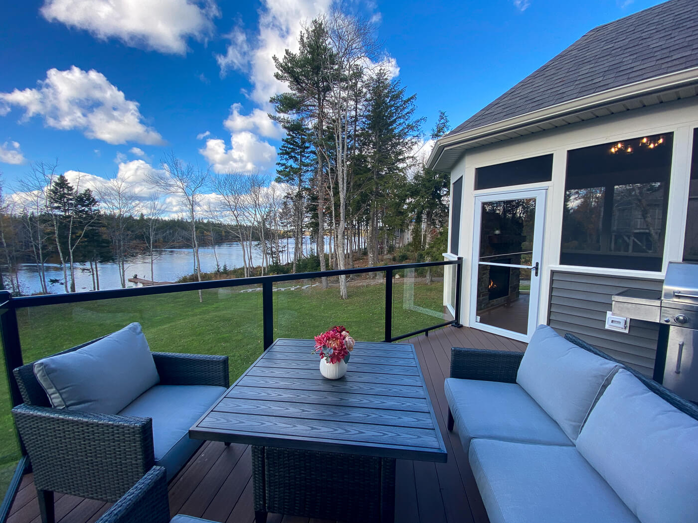 After photo of the adjacent deck, with patio furniture and center-table, looking out to the backyard and lake in Nova Scotia
