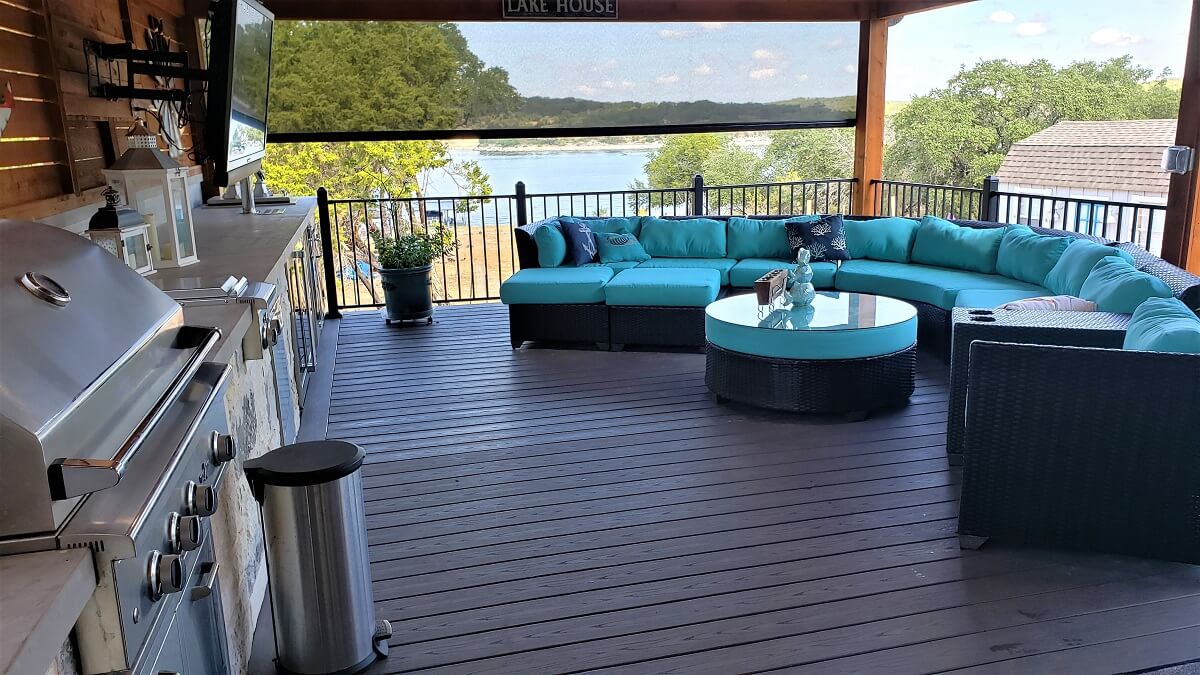 Covered deck with outdoor kitchen and seating area overlooking water