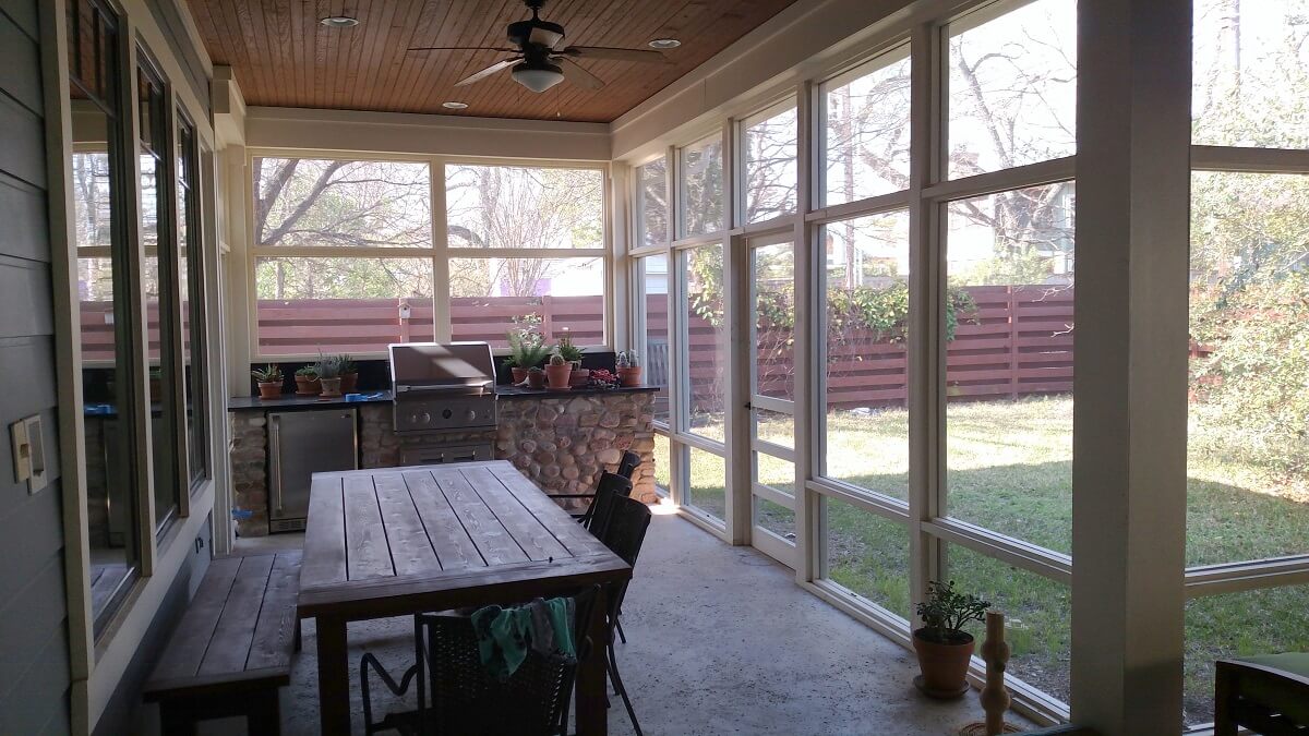 Backyard screened porch with outdoor kitchen and dining area
