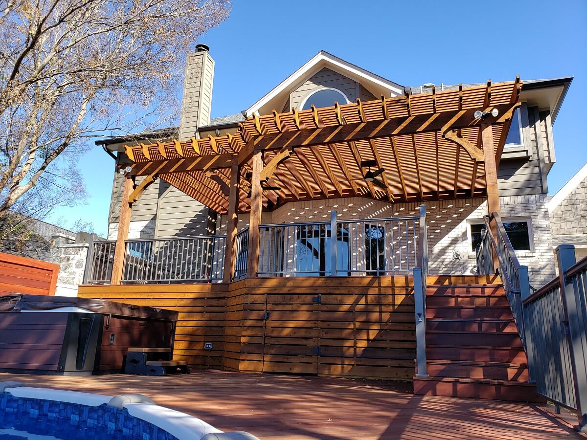 Backyard wood deck with railing and pergola