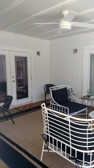 Inside of screened porch with seating area and ceiling fan