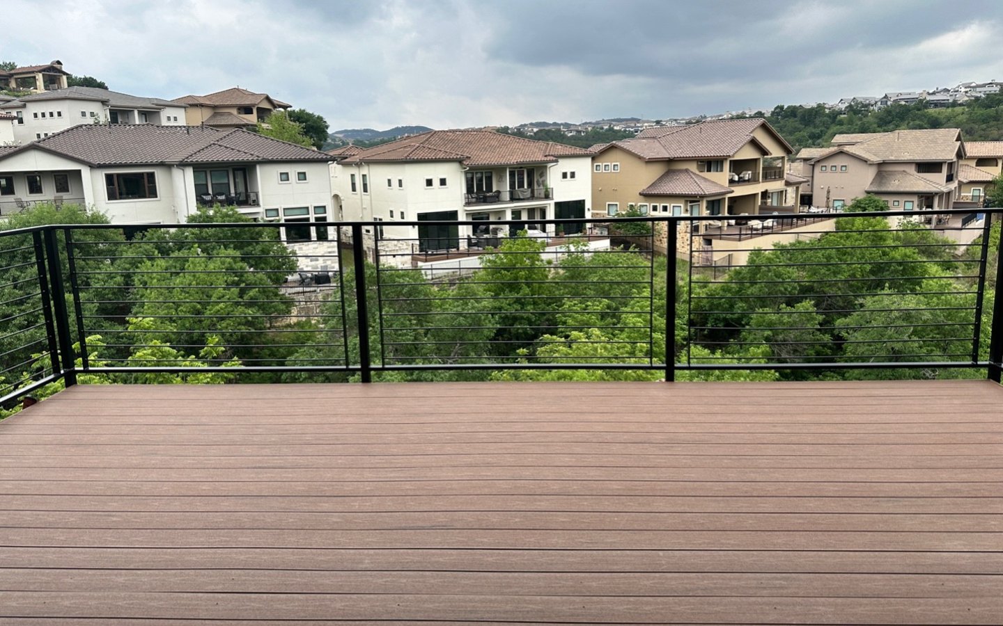 A deck with a fence and trees in the background

Description automatically generated