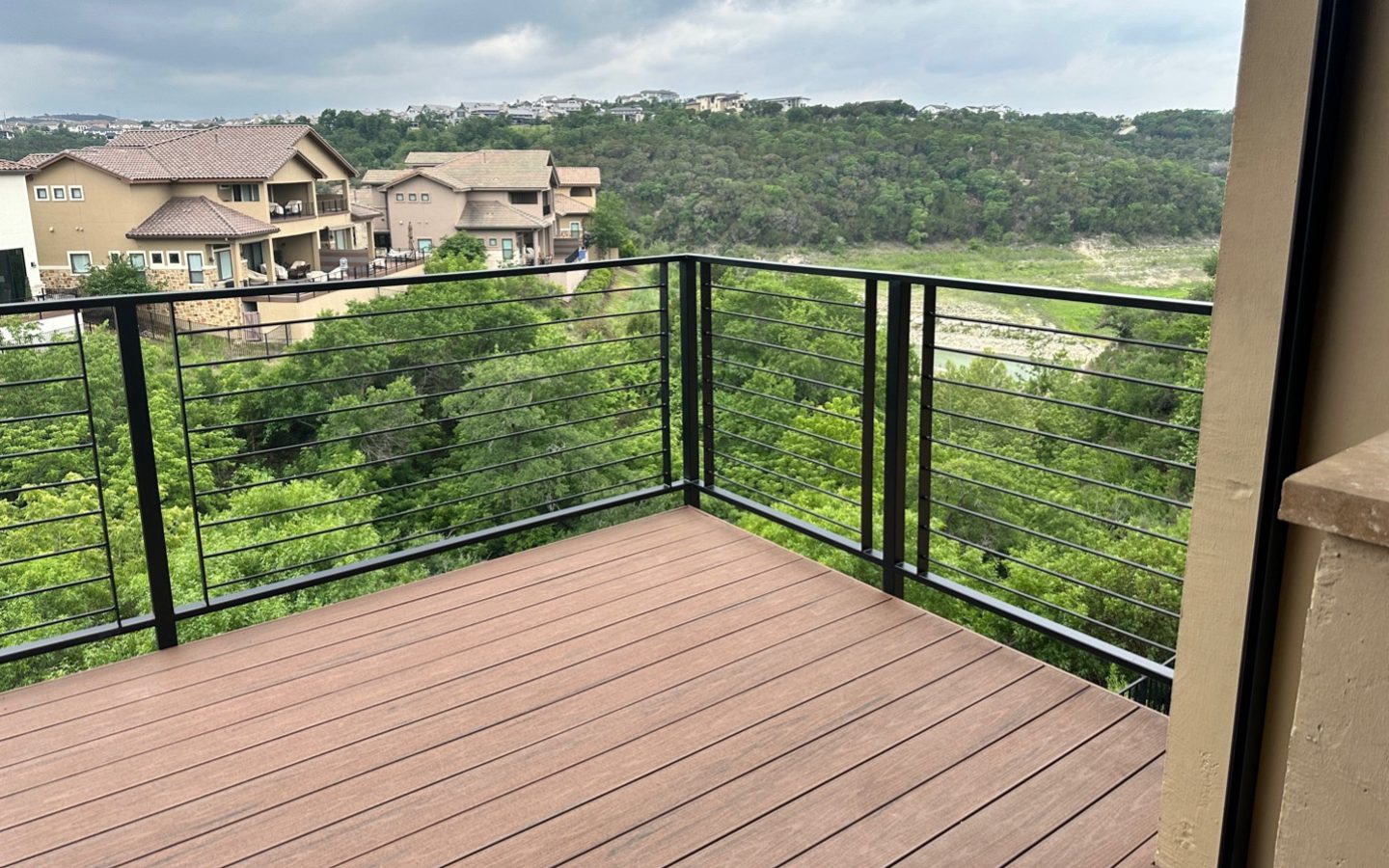 A deck with a view of a forest and houses

Description automatically generated