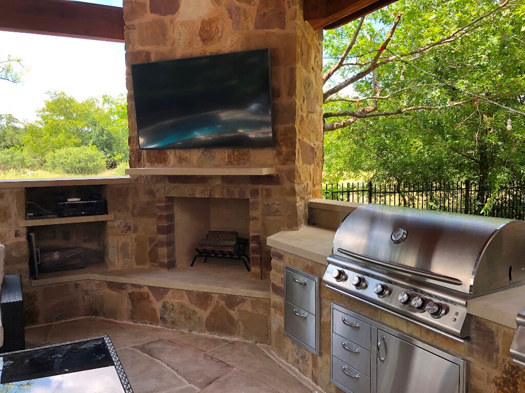 Outdoor fireplace with mounted flat TV and outdoor kitchen