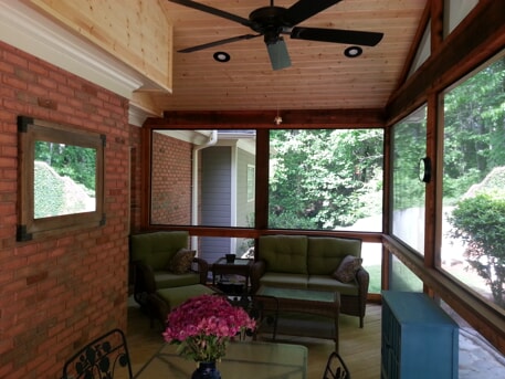 screened porch with sitting area and flowers on the table 