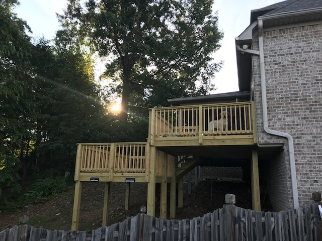 Far view of wood deck with peeking dog on railing