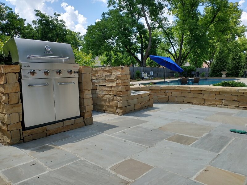 Outdoor patio with stone wall and grill area