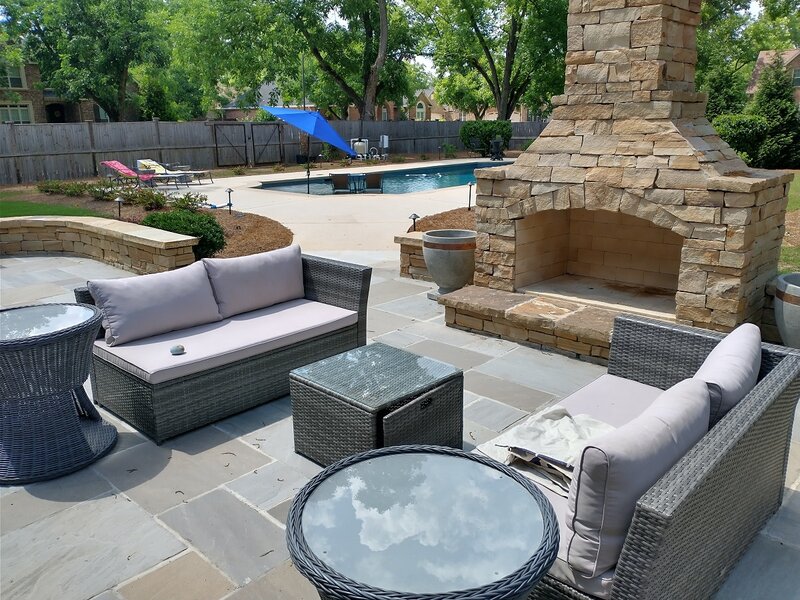 custom paver patio with furniture and fireplace feature by pool