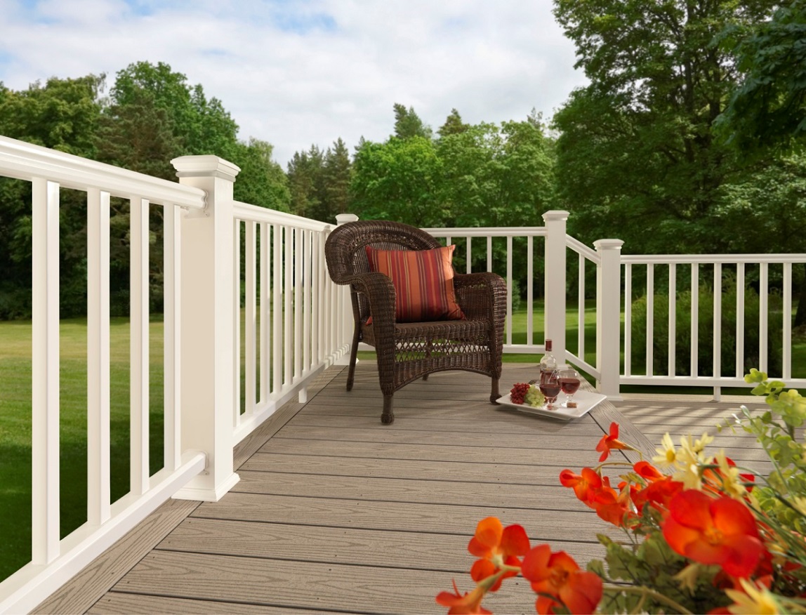 wicker chair on deck with white fence and flowers