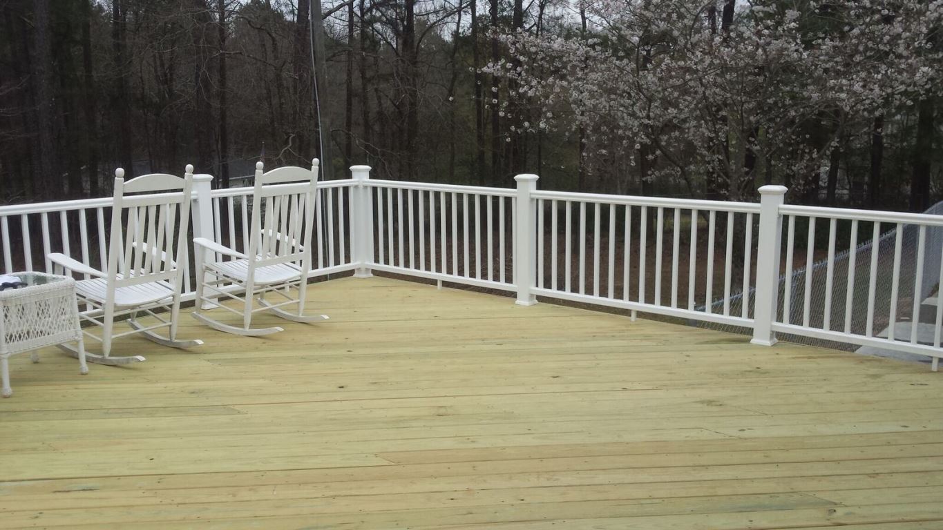 large wooden deck with white gate and rocking chairs