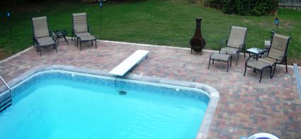 Paver patio around a pool with a diving board