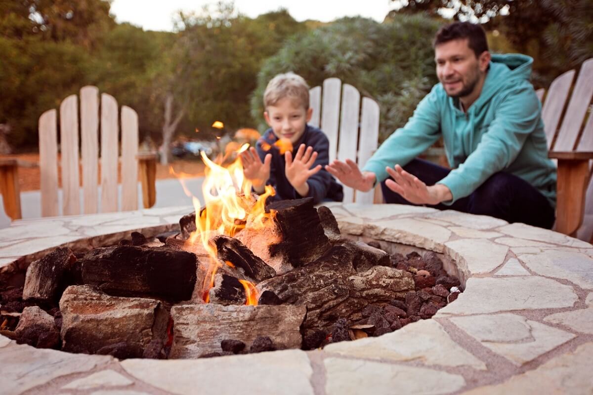 Father and son heating hands on by the fire pit