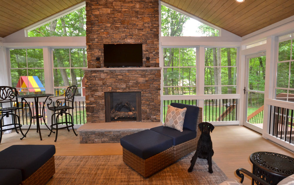 Screened porch with outdoor fireplace and black dog