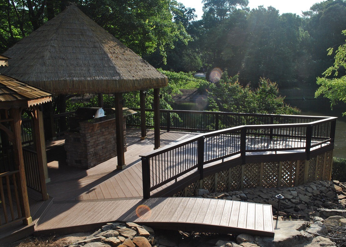 Wide view of custom wood deck with outdoor kitchen and mini bridge