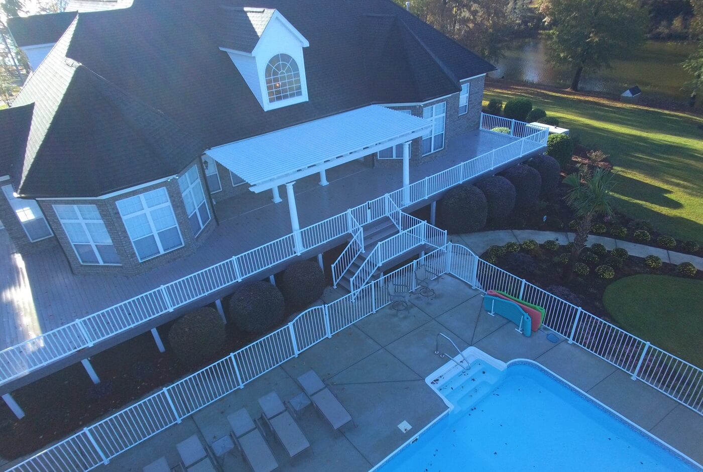 Top view of poolside elevated deck with white railing and staircase