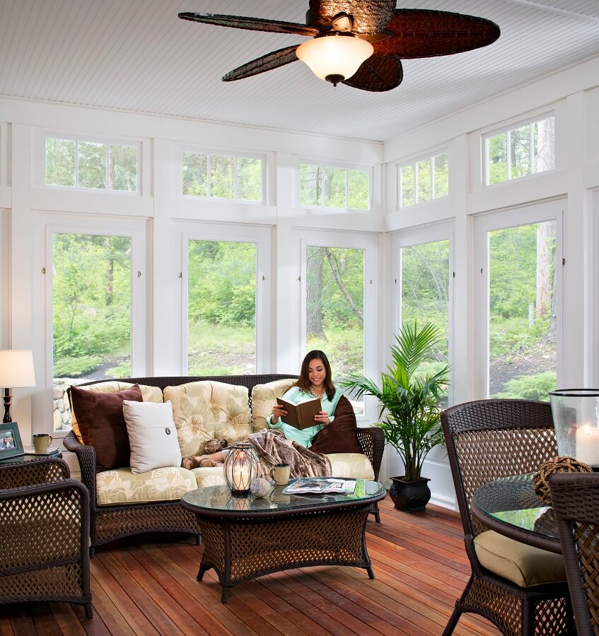 woman sitting in her sunroom with large windows