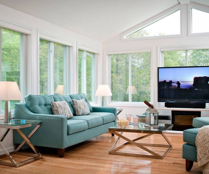 sunroom with green couch, large windows and TV
