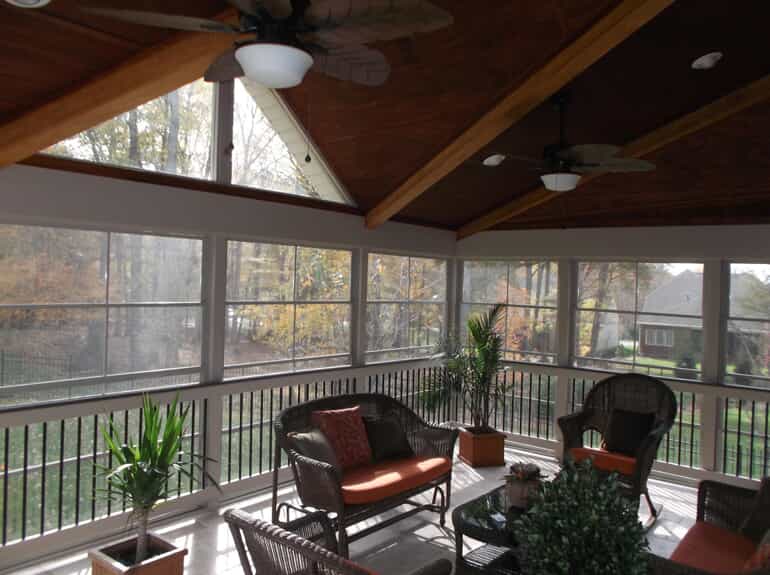Inside of a screened in porch with chairs and plants