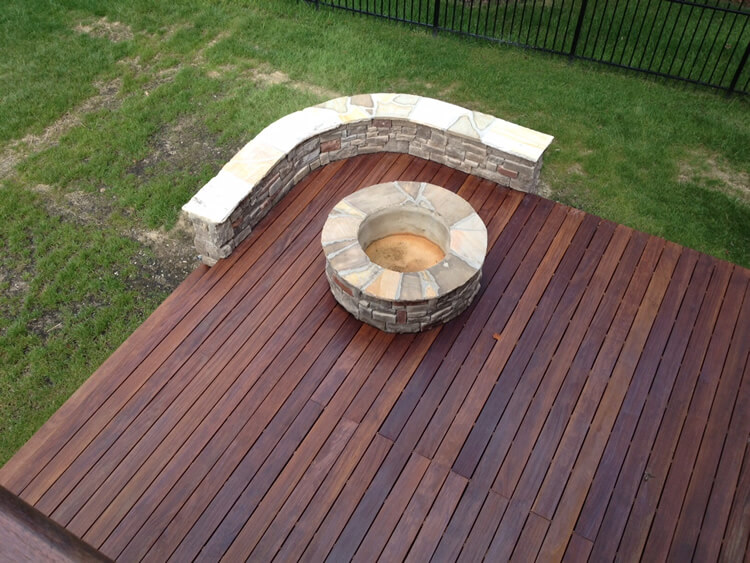 Custom backyard deck with fire pit and seating wall