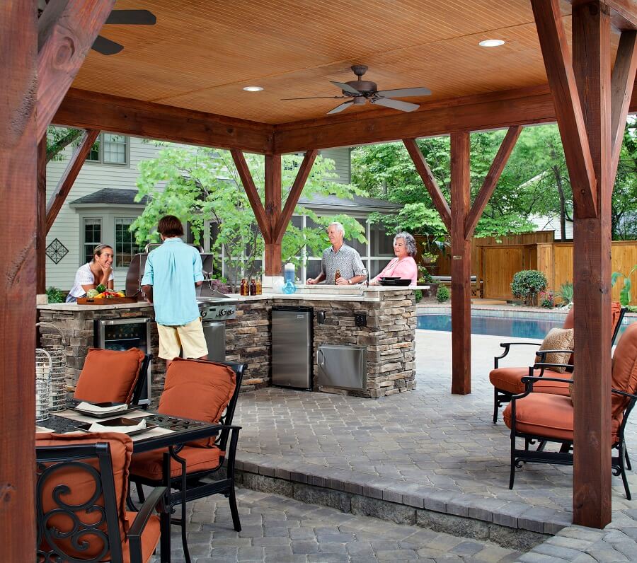 Poolside patio with outdoor kitchen and family hanging out